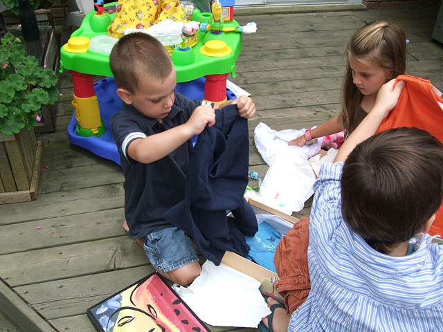 All the kids helped Andrew open his gifts. 